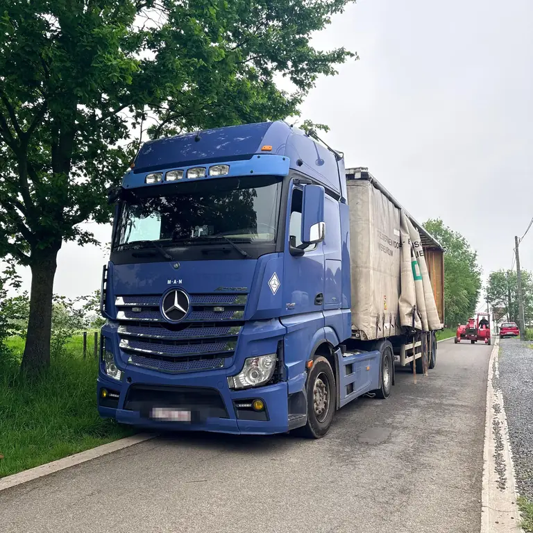 Camion bâché chargé de palettes de bois de chauffage arrivant chez un client