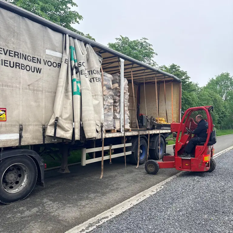Ouverture de la bâche du camion pour décharger les palettes de bûches