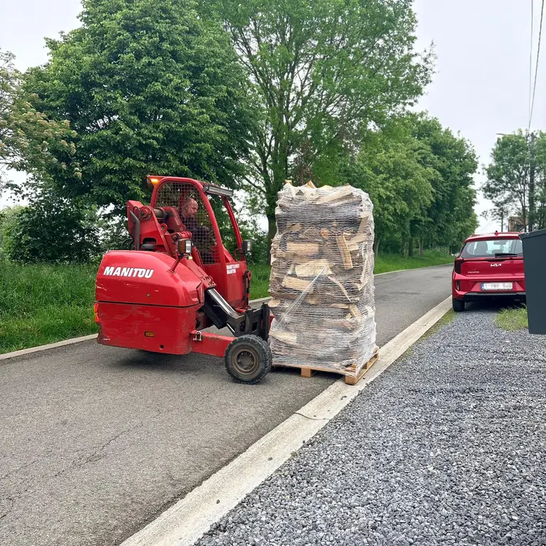 Livraison d'une palette de bois de chauffage dans une allée en gravier