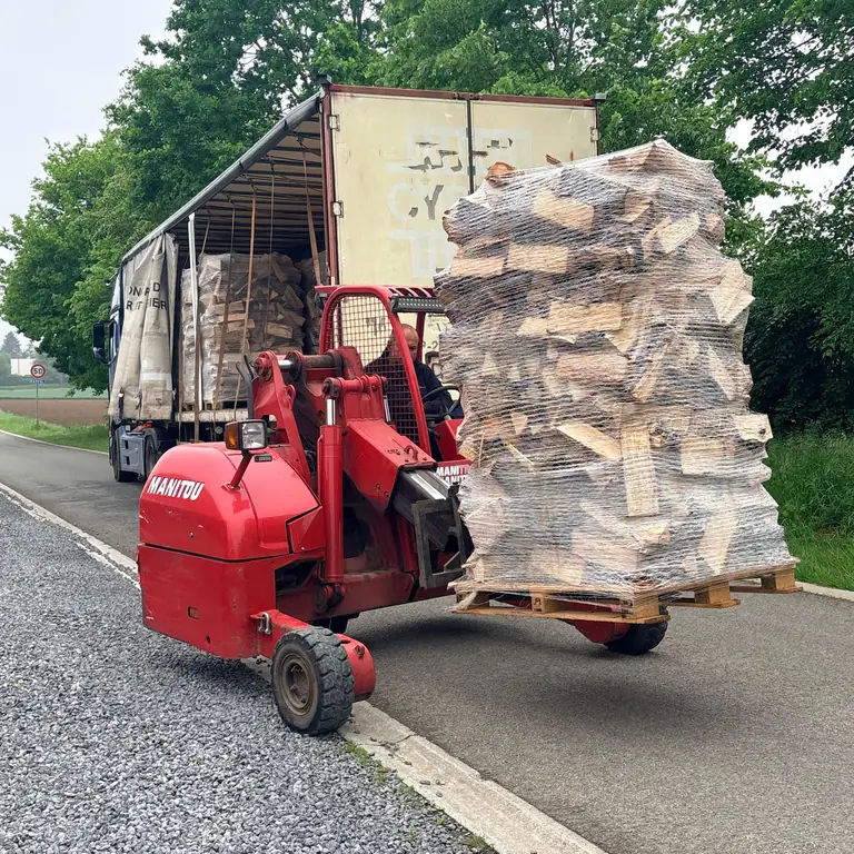 Transpalette tout-terrain Manitou sortant une palette de bûches du camion